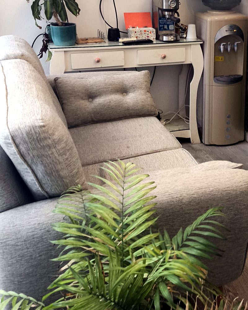 Sala de espera del consultorio Kinesiarte en Saavedra, con sillón, plantas y dispenser de agua